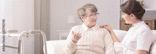 Panorama of a senior woman talking to a young, female caregiver in a private rehabilitation center