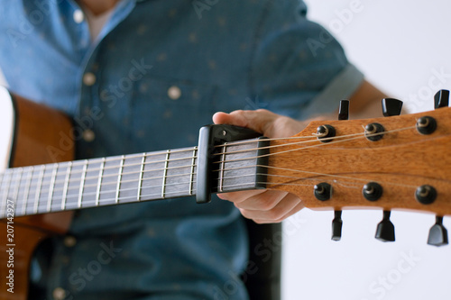 Handsome and cheerful guy musician in a shirt playing guitar