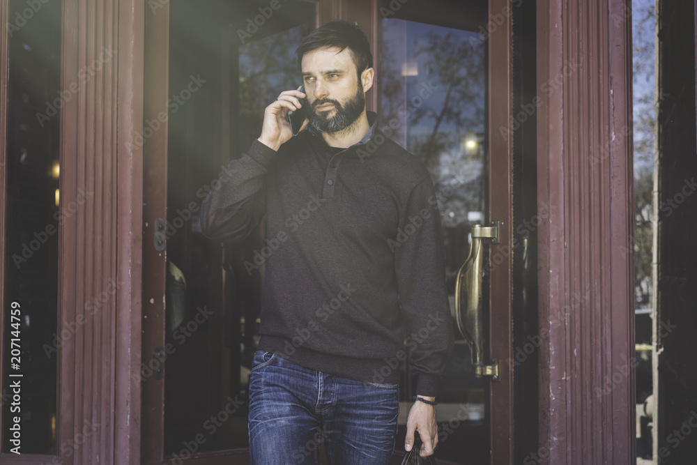 Casual professional entrepreneur using smartphone outside.Bearded Man in talking on a mobile phone.Sunlights effects