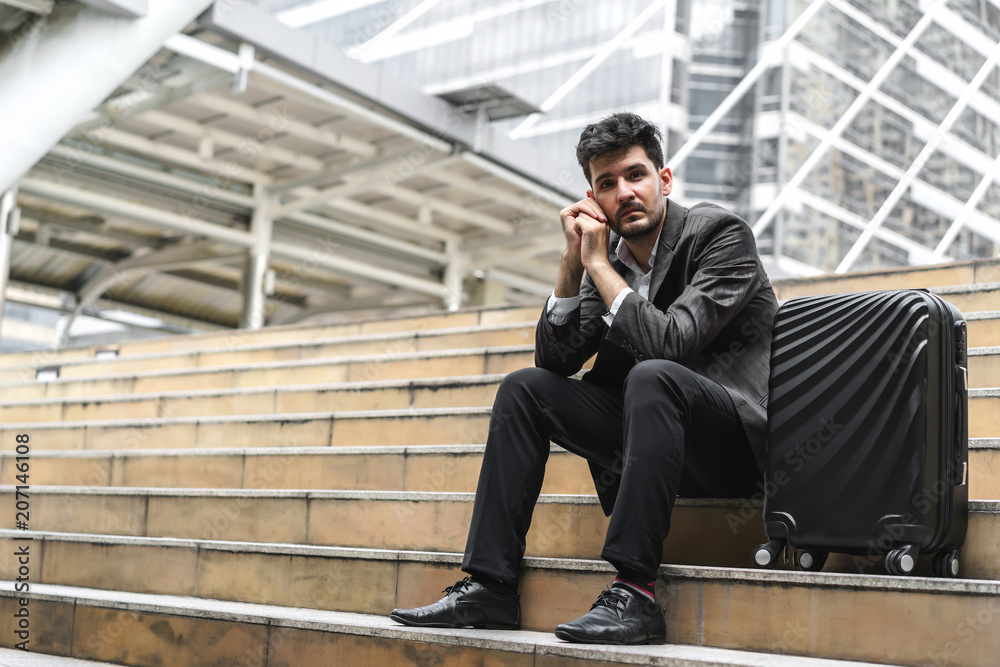 Business man sitting on stair with luggage in the routine of working with determination and confidence. concept of business trip travel and transportation. Business man sitting on stair with luggage in the routine of working with determination and confidence. concept of business trip travel and transportation.