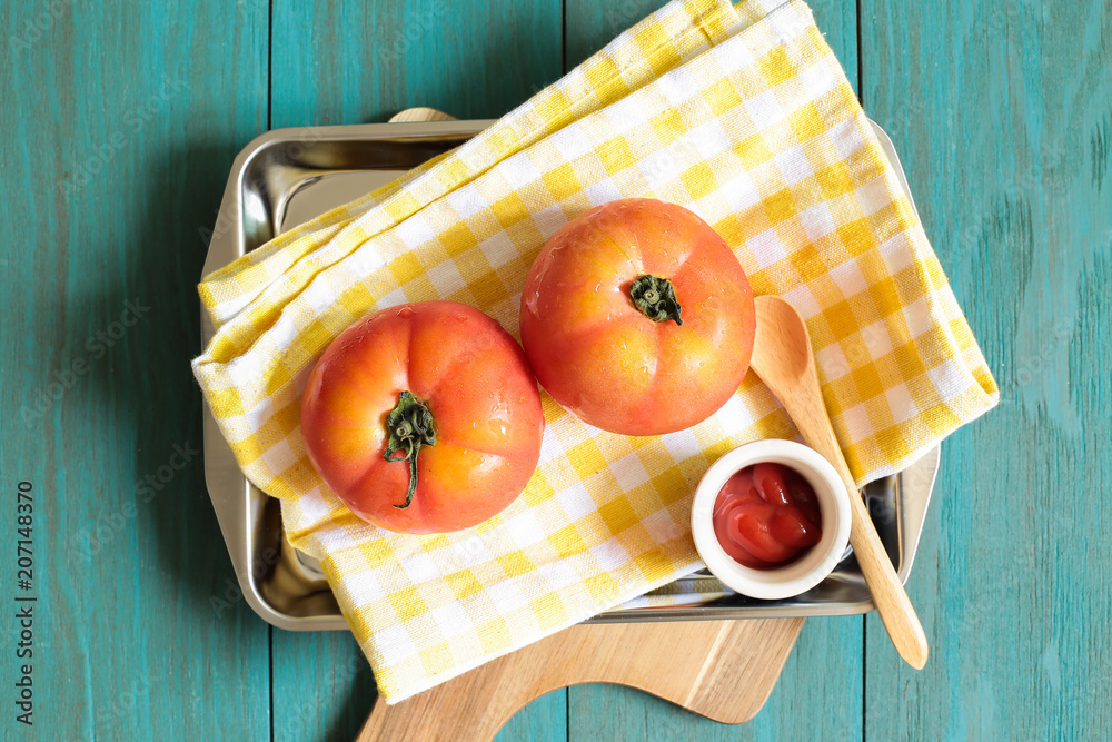 Fresh tomatoes and ketchup on vintage style green painted wooden table