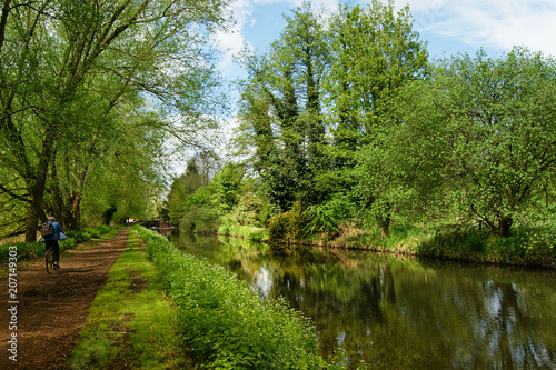 Path along the river, channel with cyclist. Scenic summer landscape