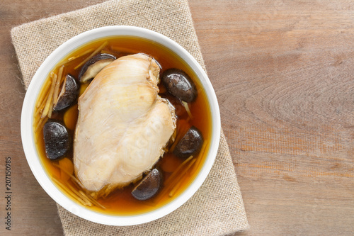 steamed chicken breast with soy sauce in a ceramic dish on wooden table, top view. homemade style healthy food concept