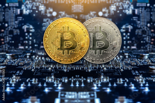 Golden and silver bitcoins standing on circuit board, business concept. © surachat