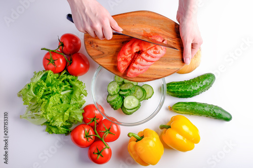 Woman cutting fresh red tomatoes on wooden board ingredients for salad