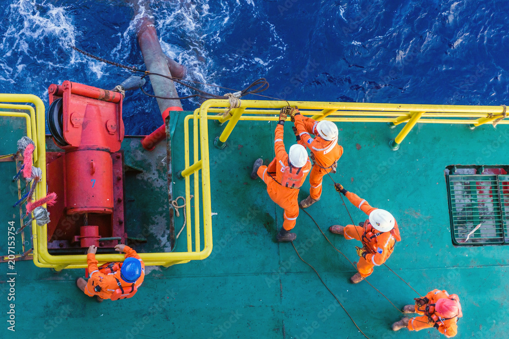 Offshore workers working together during anchor handling job on a construction barge at oil