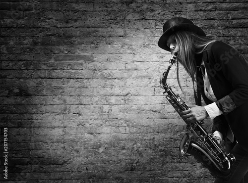Sticker Woman plays the saxophone against the background of an old brick wall