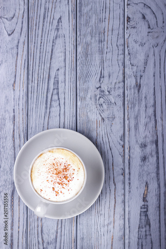 Cup of cappuccino with cinnamon on a gray wooden background. Top view. Free space