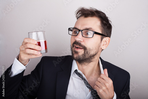 Disheveled bearded man in suit with a glass of whiskey