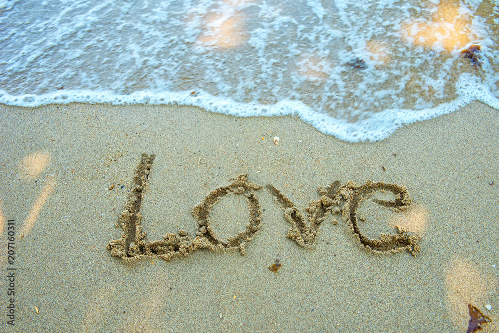 Write the word love on the beach. Soft focus wave. Write the word love on the beach. Soft focus wave.