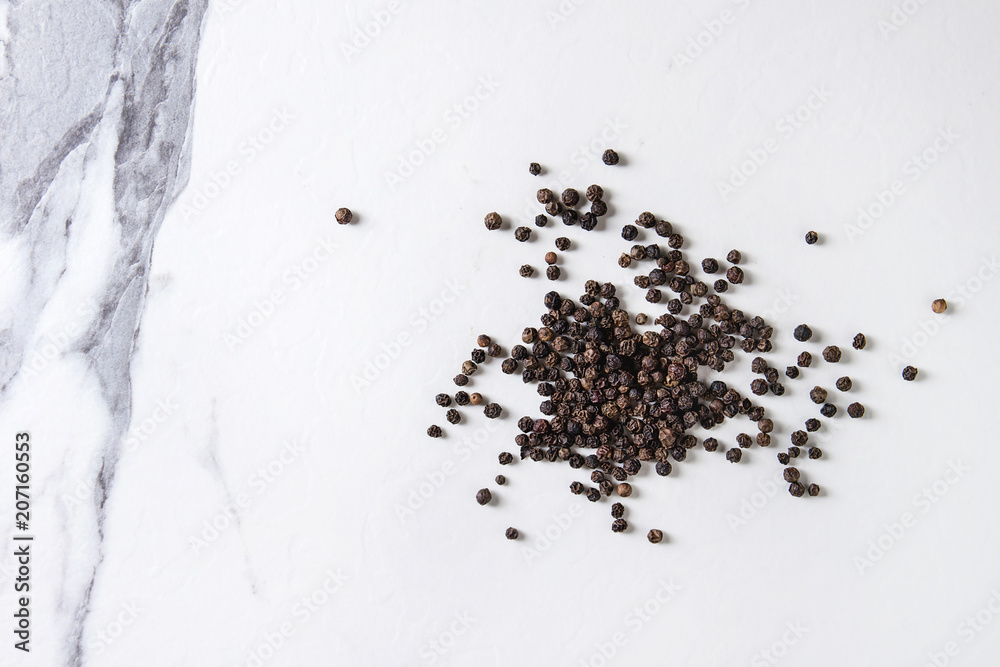 Heap of black pepper peppercorns over white marble texture background. Top view, space. Heap of black pepper peppercorns over white marble texture background. Top view, space.