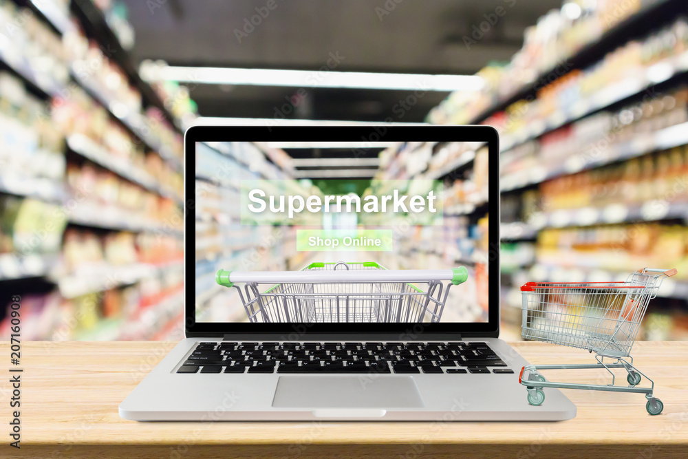 laptop computer on wood table with supermarket aisle blurred background online shopping concept laptop computer on wood table with supermarket aisle blurred background online shopping concept