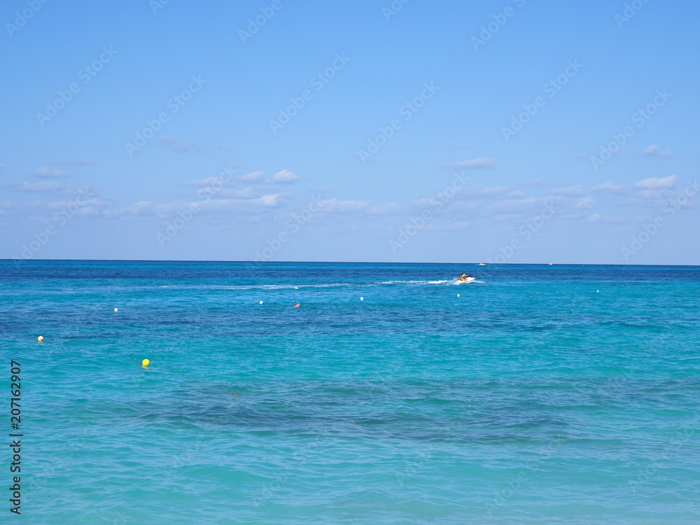 Awesome clean turquoise waters of Caribbean Sea landscape with motor boat and horizon line at Cancun city in Mexico