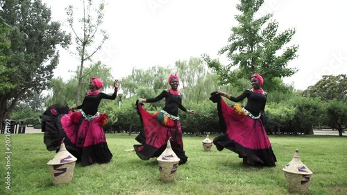African women are dancing a folk traditional dance on a grass meadow, in traditional costumes with wicker baskets, sunny, trees' background, African costumes, traditions, African culture, tribes