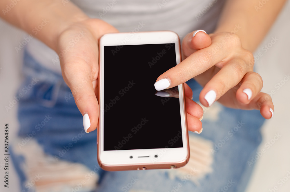 Woman in jeans looks at mobile phone smartphone touch device fashion beauty Woman in jeans looks at mobile phone smartphone touch device fashion beauty