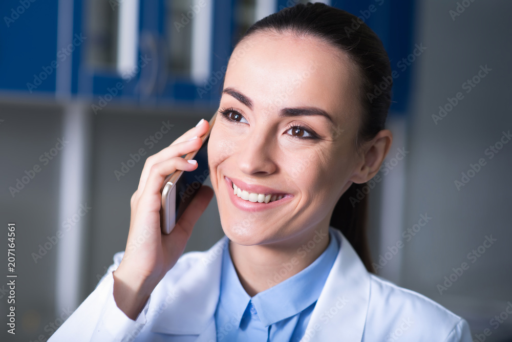 Cute pleasant expert keeping cellphone near her head and smiling. Cute pleasant expert keeping cellphone near her head and smiling.