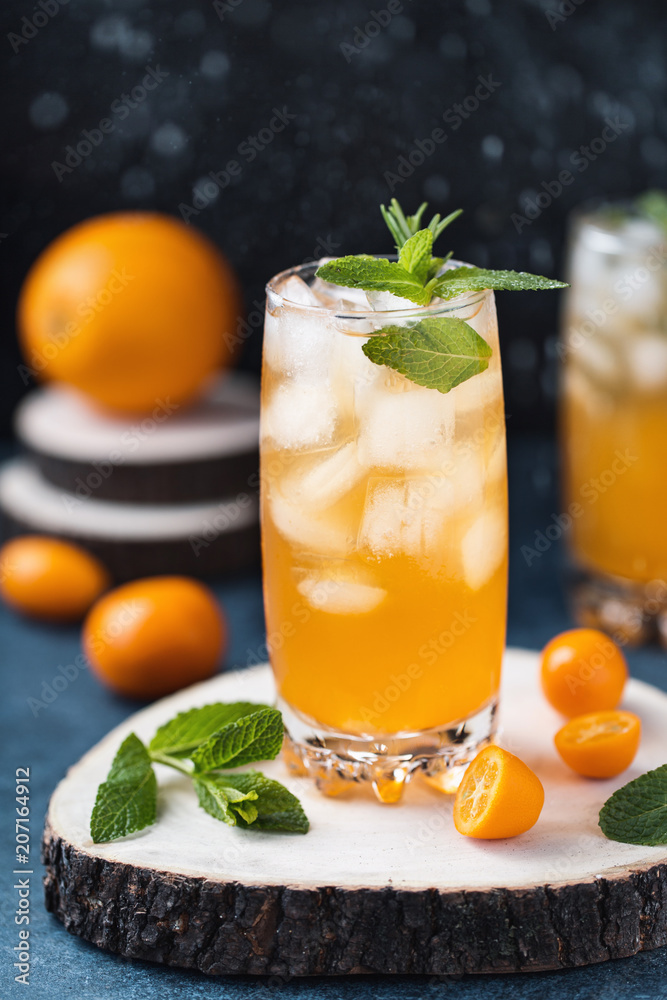 Fresh summer cocktail with orange juice and ice cubes. Glass of orange soda drink on dark background Fresh summer cocktail with orange juice and ice cubes. Glass of orange soda drink on dark background