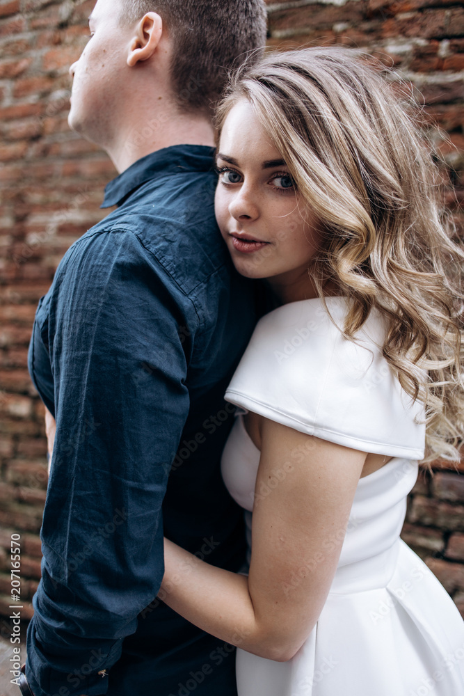 Fototapeta premium The lovely couple in love embracing and standing on the street
