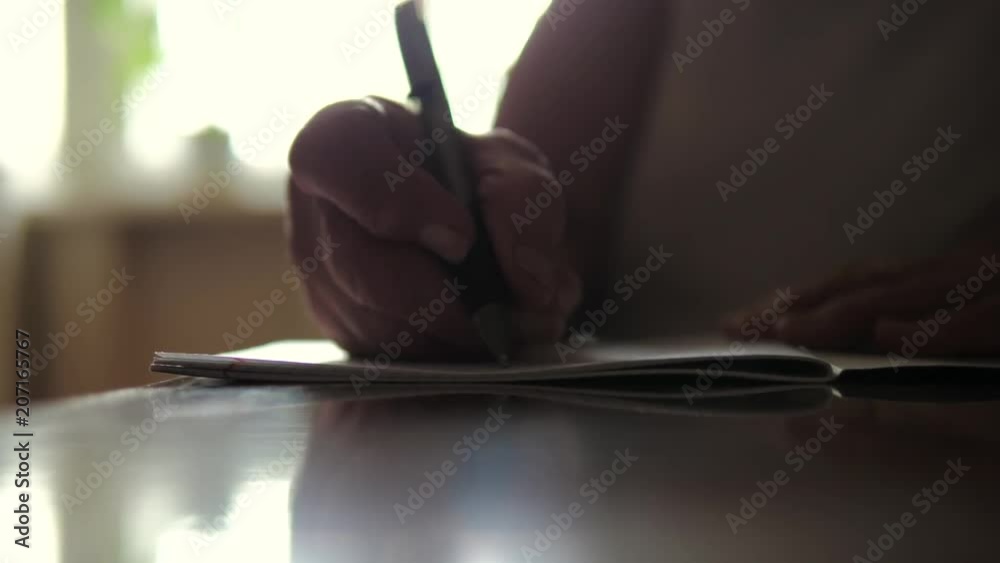 Closeup Of An Old Woman Hand Writing On Paper Sitting At A Table Closeup Of An Old Woman Hand Writing On Paper Sitting At A Table