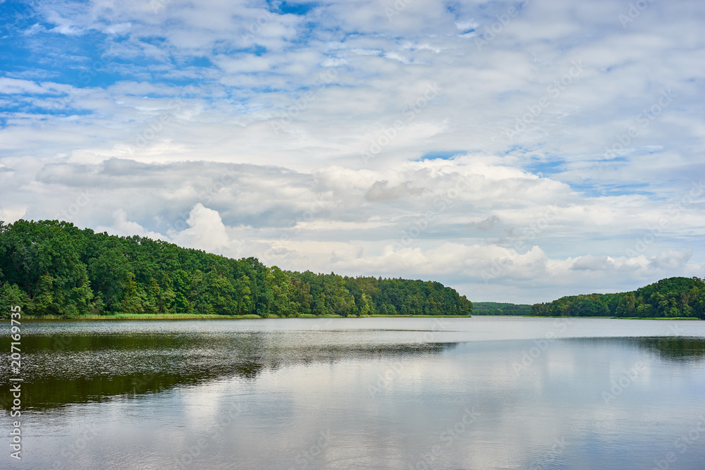 Summer landscape with forest lake under a blue cloudy sky. Kuyavian-Pomeranian, Poland