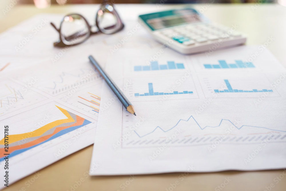business office desk workplace report graph with pencil, calculator and eyeglasses on wooden table business office desk workplace report graph with pencil, calculator and eyeglasses on wooden table
