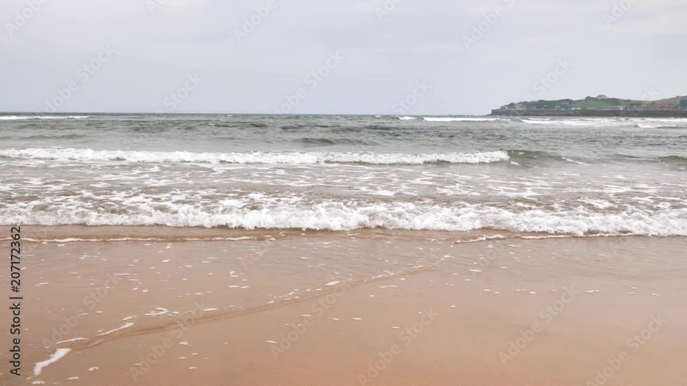 ebb of the ocean at city's Gijon beach in Asurias in cloudy day with brown sand ebb of the ocean at city's Gijon beach in Asurias in cloudy day with brown sand