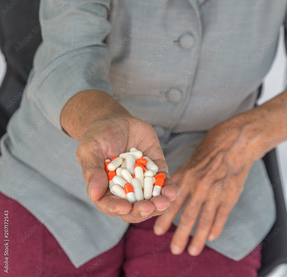 senior woman holding pill in her hand senior woman holding pill in her hand