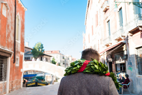young man walking the streets of venice after graduation ceremony with traditional laurel crown at venice university