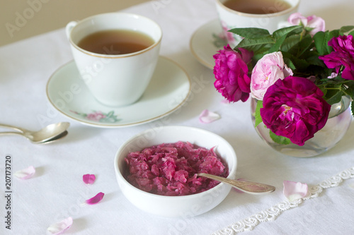 Obraz na płótnie Jam from the petals of the Damascus rose, a cup of green tea and a vase of roses on a light table. Rustic style. w salonie