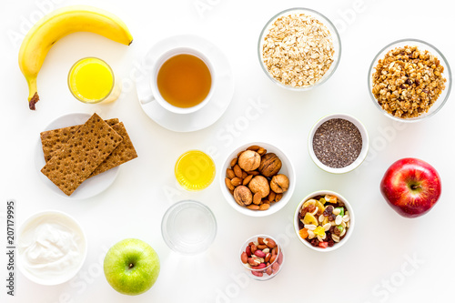 Ingredients for healthy breakfast. Fruits, oatmeal, yogurt, nuts, crispbreads, chia on white background top view