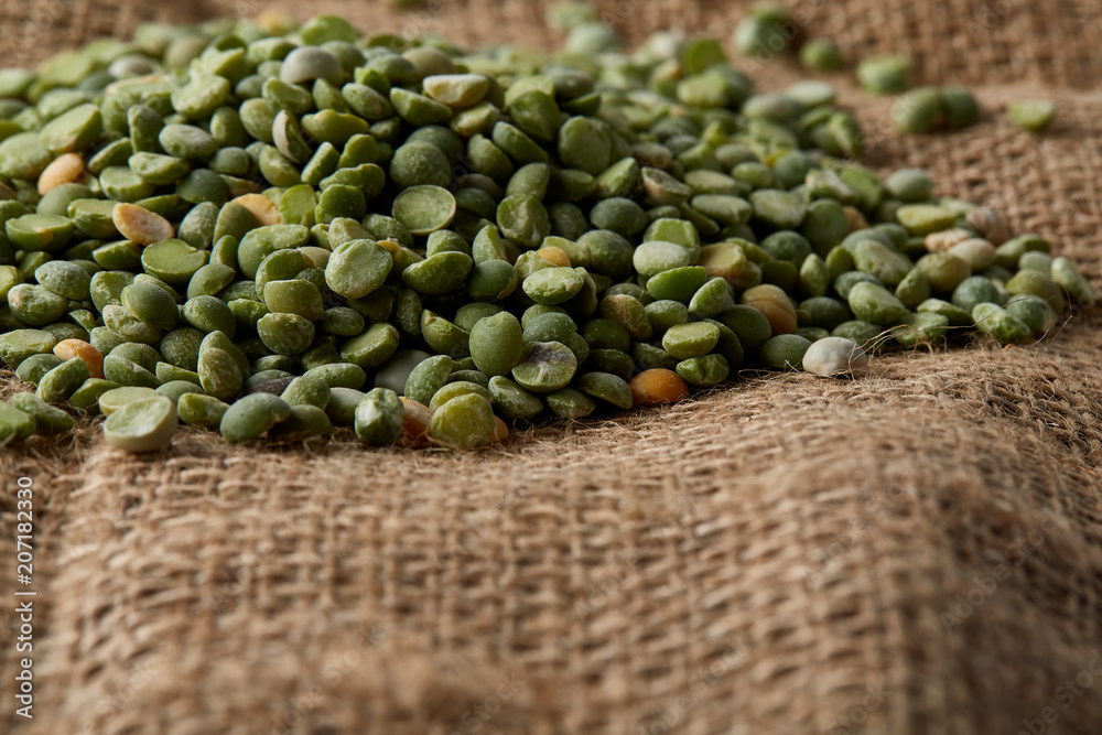 Pile of green peas on burlap tablecloth, close-up, top view, selective focus, shallow depth of field.