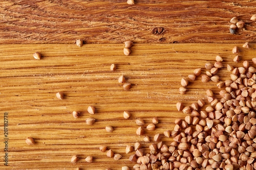Buckwheat groats on wooden background, top view, close-up, selective focus.
