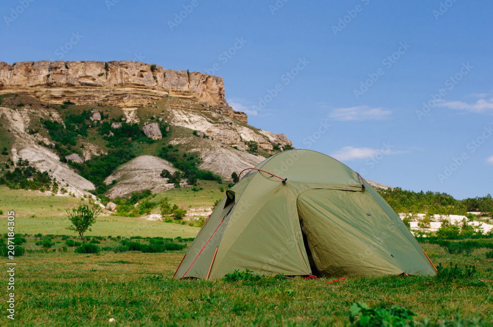 Tourist tent in front of rocky cliff