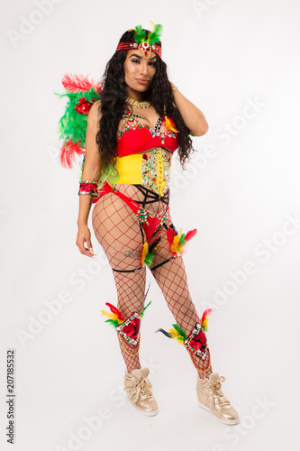Fit young dark haired hispanic woman in Carnaval costume and athletic shoes posing on clean white background