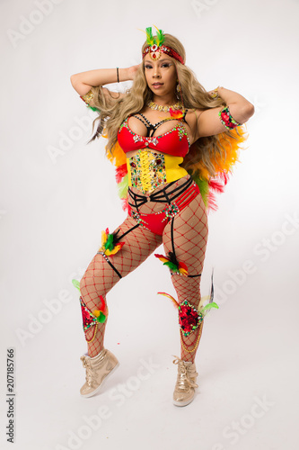 Fit young blonde hispanic woman in Carnaval costume and athletic shoes posing on clean white background