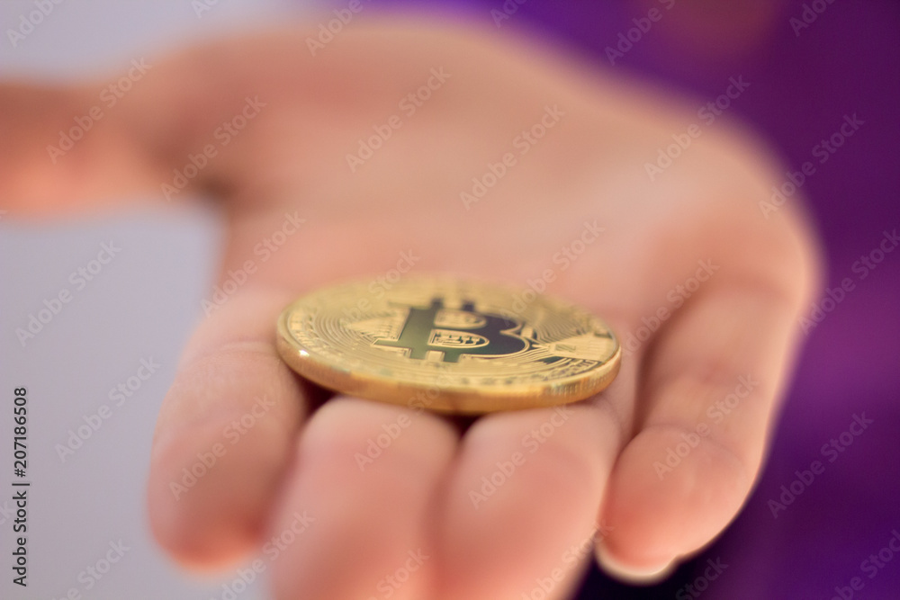 A hand holding Golden Bitcoin - virtual money on blur background. A hand holding Golden Bitcoin - virtual money on blur background.