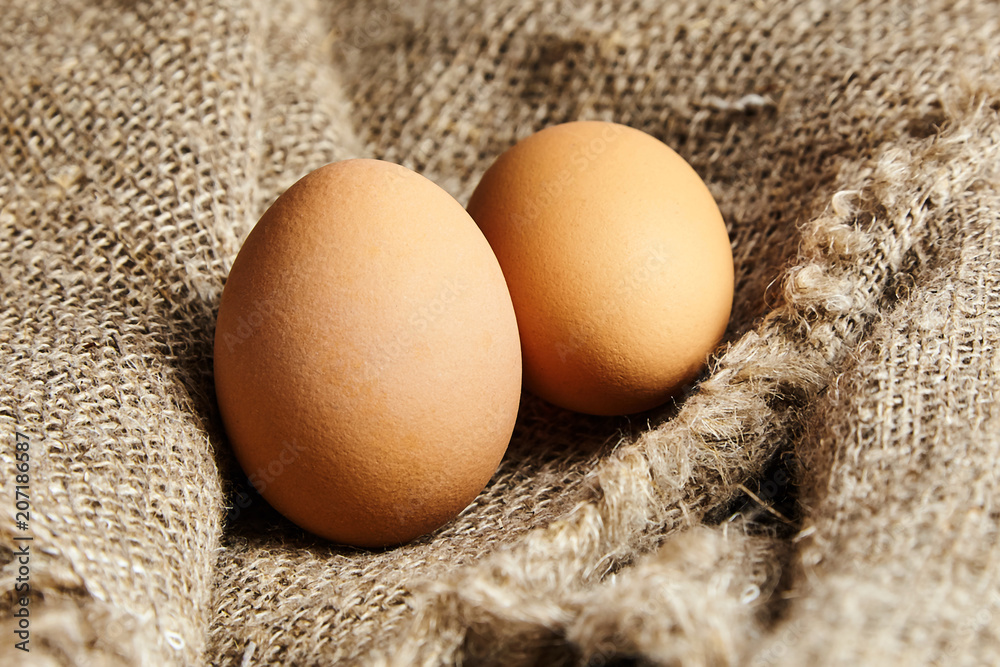 Two brown chicken eggs in on sackcloth texture Two brown chicken eggs in on sackcloth texture