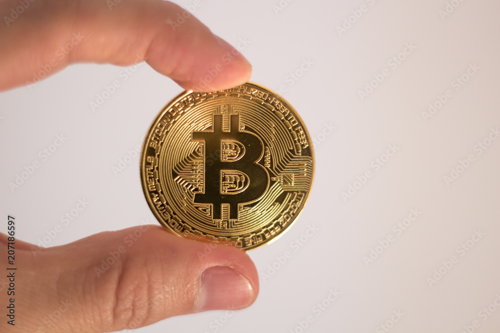 A hand holding Golden Bitcoin - virtual money on blur background.