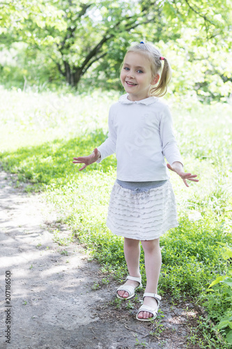 Portrait of a little beautiful girl in white clothes in the park © Gribanov