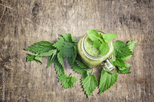 Fototapeta Naklejka Na Ścianę i Meble -  Fresh green smoothie with wild nettle and other herbs in mason jar on rustic wooden background.