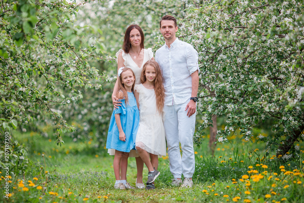 Adorable family in blooming cherry garden on beautiful spring day Adorable family in blooming cherry garden on beautiful spring day