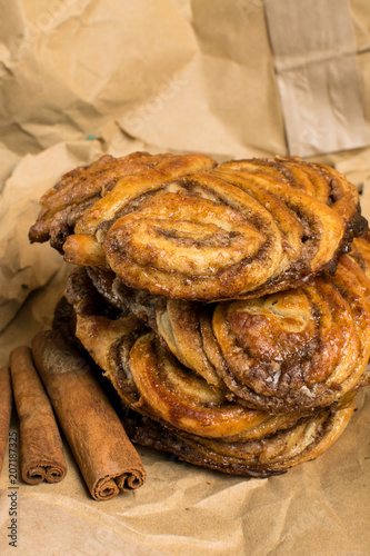 homemade sweet cinnamon rolls on paper bag with sticks of cinnamons photo