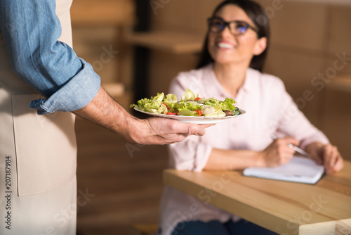 waiter serving salad for businesswoman