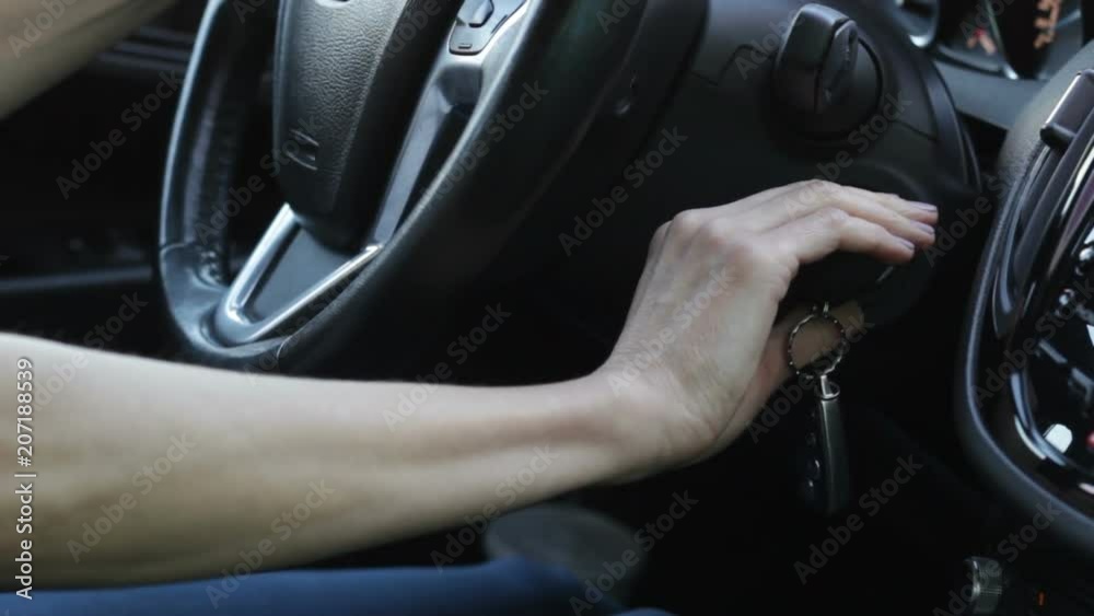 Woman's hand is starting car. First test drive. Close up of helm, auto key. Woman's hand is starting car. First test drive. Close up of helm, auto key.