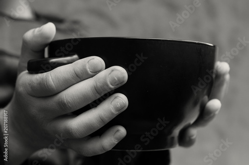 The palms of the hungry boy hold an empty plate.