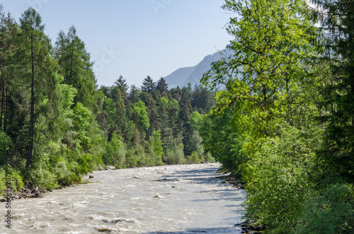 View of Inn river through lush landscape with green trees and meadow mountains and road