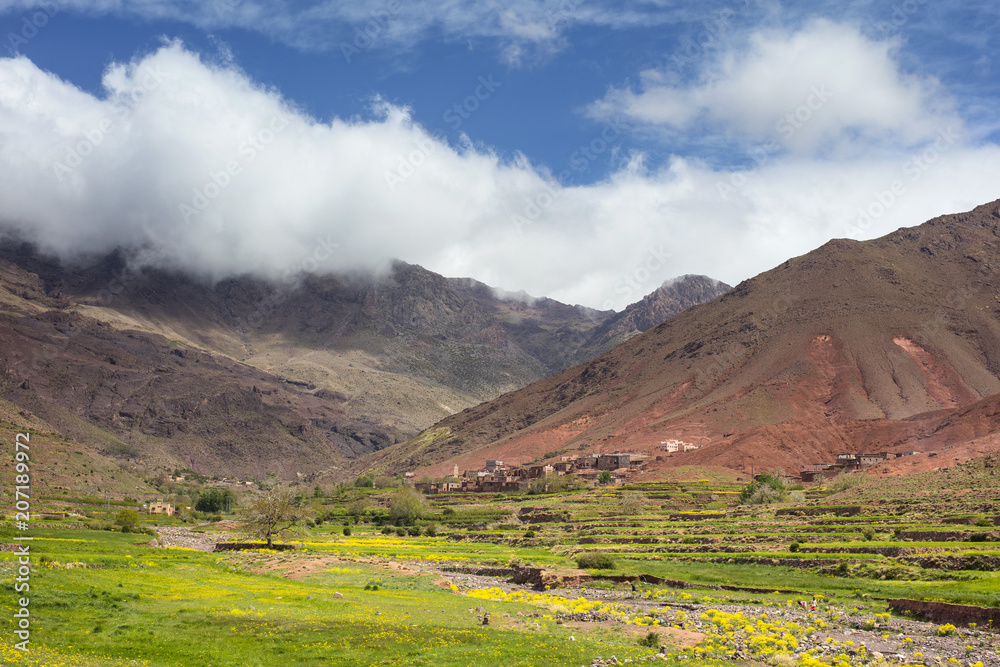 Fototapeta premium red mountains with clouds and green valley in Morocco