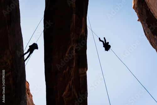 People rappelling off of Morning Glory Arch in Moab, Utah.  photo