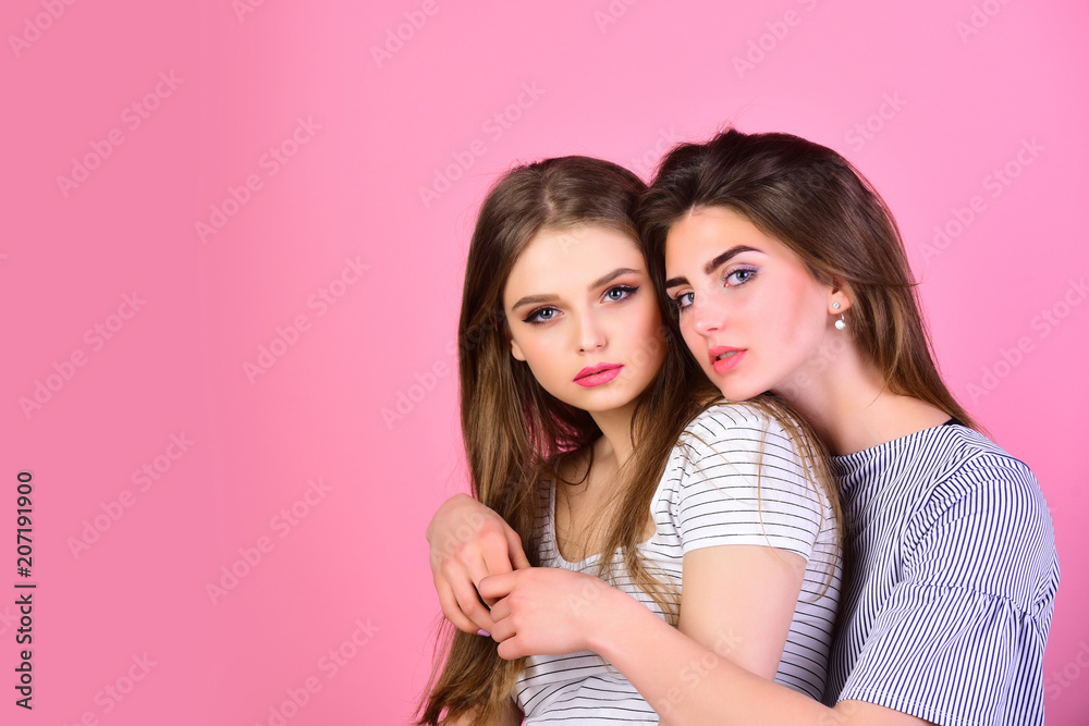 couple of sexy girls embrace on pink bakcground, copy space. family falues of two sisters. friendship of female friends with pretty face makeup and long beautiful hair. fashion and beauty concept. couple of sexy girls embrace on pink bakcground, copy space. family falues of two sisters. friendship of female friends with pretty face makeup and long beautiful hair. fashion and beauty concept.