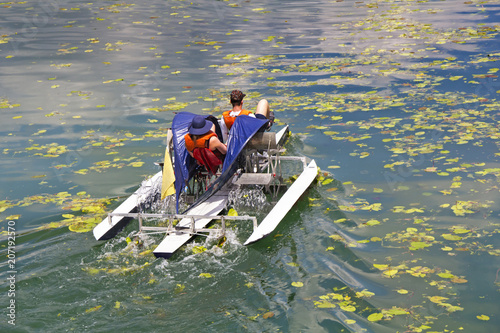 Man and woman ride with floating pedal bicycle boats across the lake photo